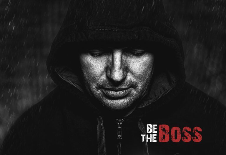 Das Foto zeigt einen jungen Mann mit Kaputze auf, er schaut nach unten, die Augen sind nicht zu sehen, das Foto ist in Schwarz Weiß