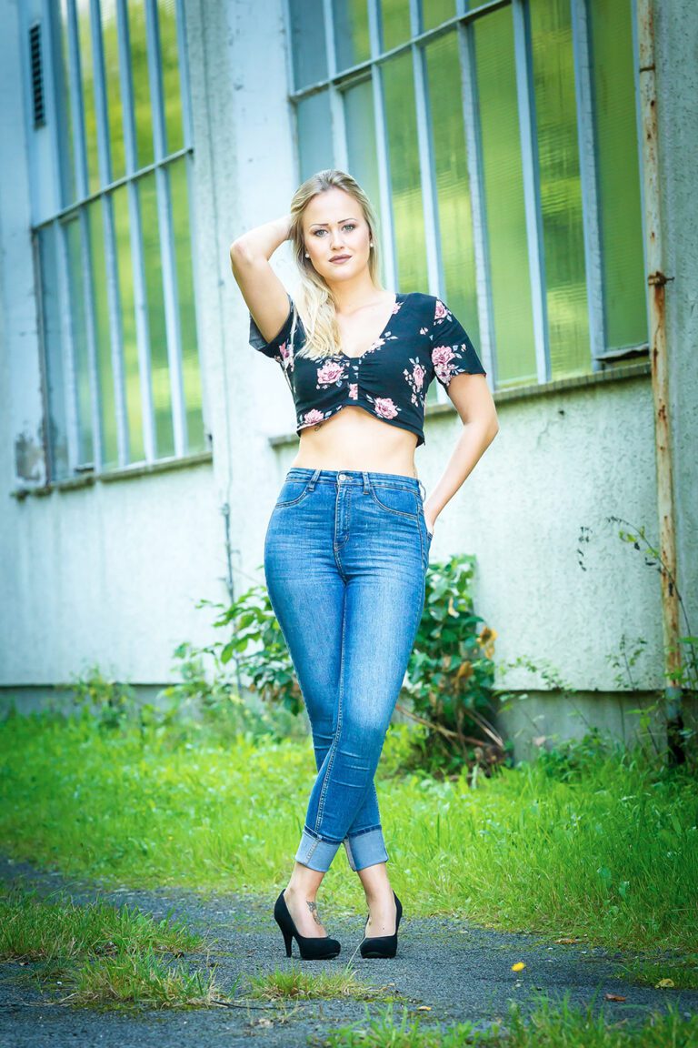 Foto zeigt eine Frau vor einem alten Gebäude im Sommeroutfit, Bauchfrei und High Heels