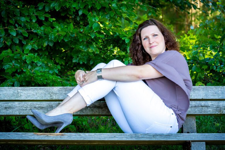 Foto zeigt eine Frau auf einer Bank in Sommeroutfit und High Heels