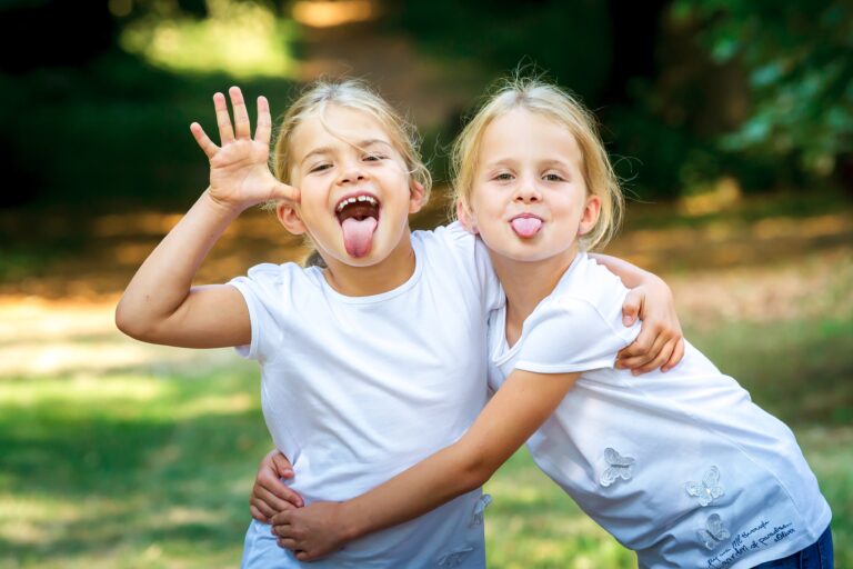 Foto zeigt zwei junge Mädchen die ihre Zunge in die Kamera strecken und Spaß dabei haben.