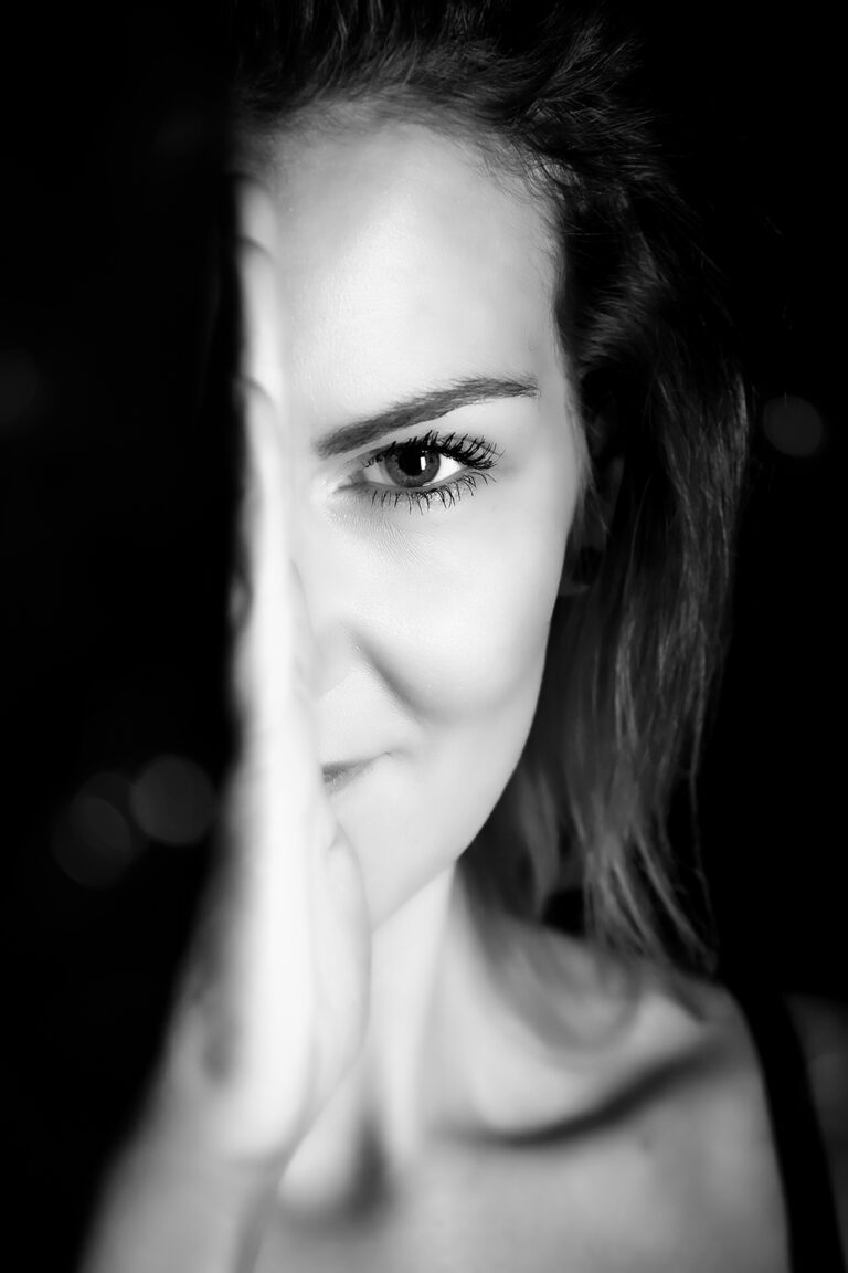 Das Foto zeigt eine junge Frau, man sieht nur eine hälfte des Kopfes, die andere liegt im Schatten.