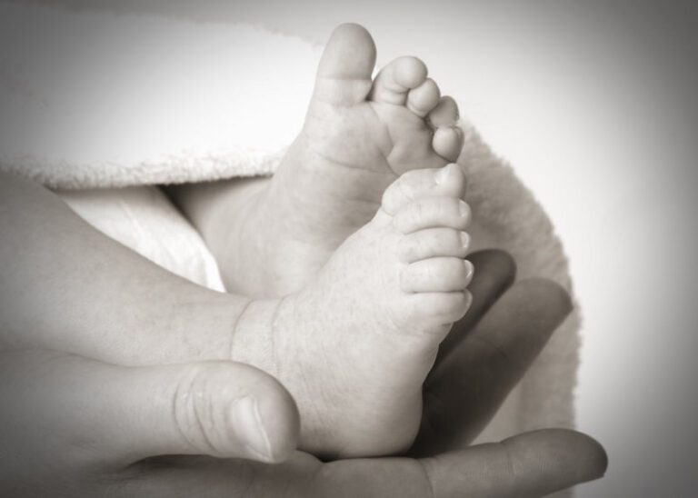 Das Foto zeig eine Erwachsenenhand hält Babyfüße
