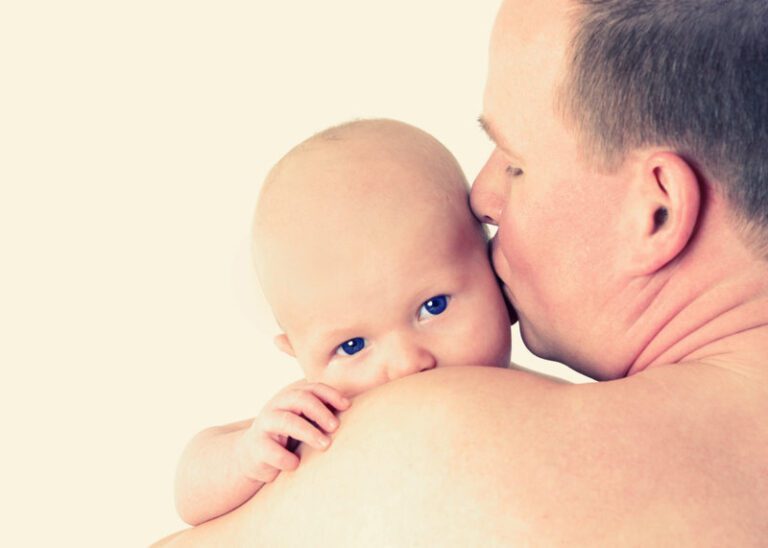 Das Foto zeig ein Baby auf dem Arm seines Vaters