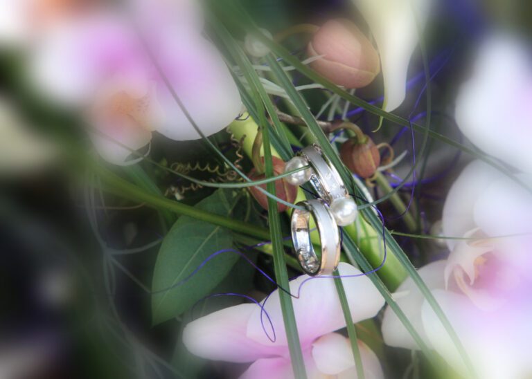 Das Foto zeig Eheringe in einem Blumenstrauß