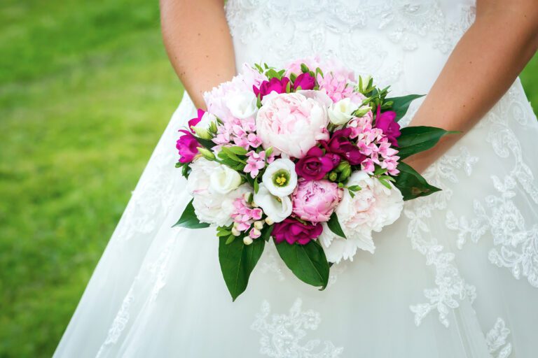 Foto zeigt wie eine Braut ihren Brautstrauß hält, zu sehen sind nur die Blumen und das Kleid